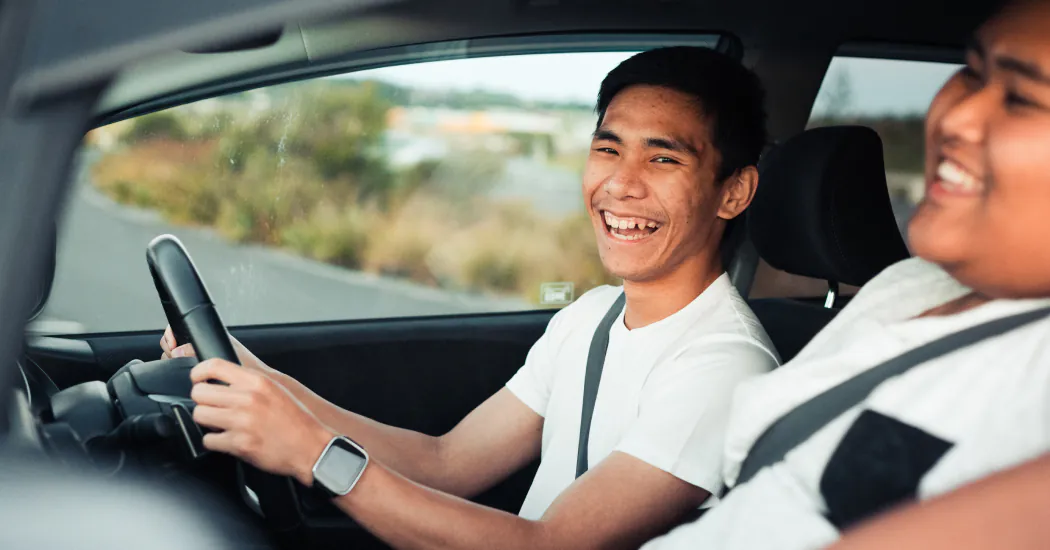 Man in car's driver's seat smiles at camera