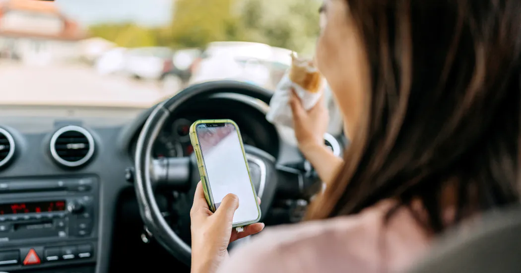 A woman using her phone while driving a car