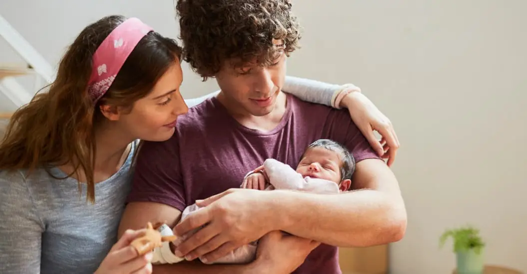 Mum and dad holding and hugging their newborn baby