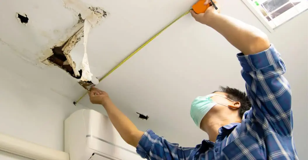 Man repairing his ceiling after water damage
