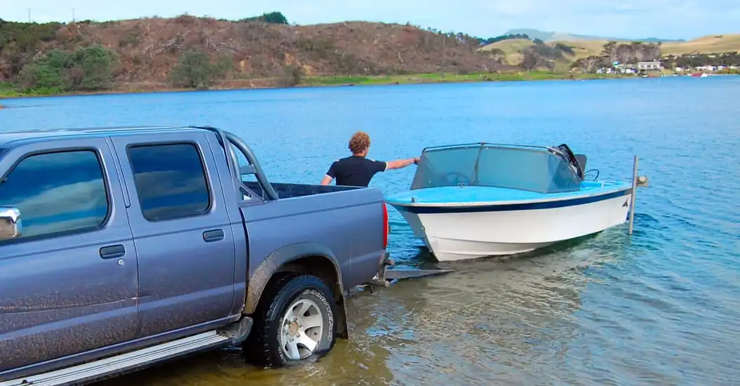 Man launching his boat into the water off the back of his ute